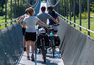 Cyclists cross the Himalayan footbridge over the Rhône
